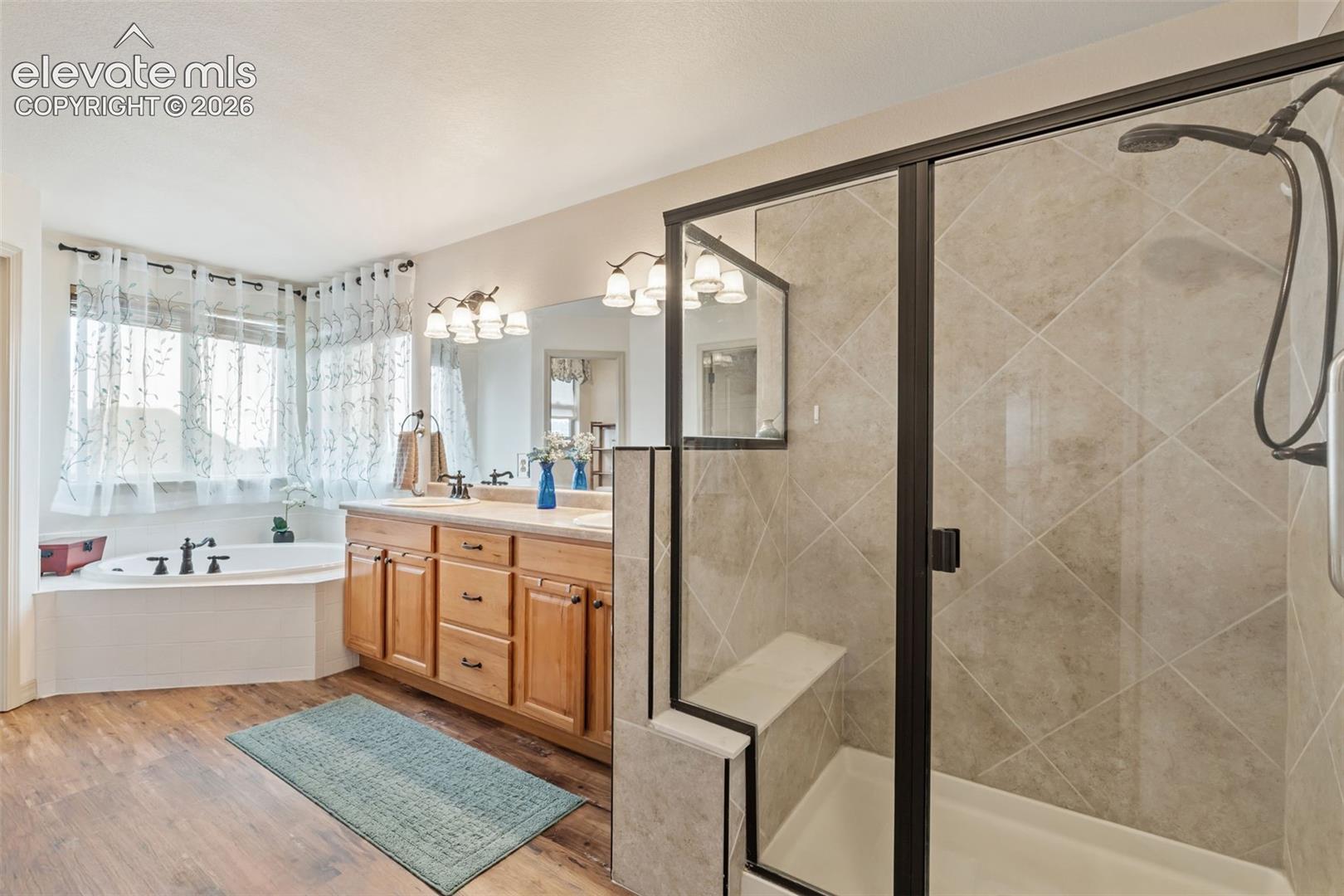 Bathroom featuring a glass-enclosed shower with tile surround, a built-in shower bench, and a dual shower head