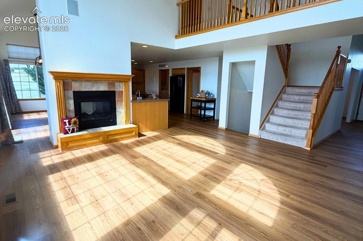 Wood-finish flooring throughout, fireplace with tile surround, wood mantel, and hearth