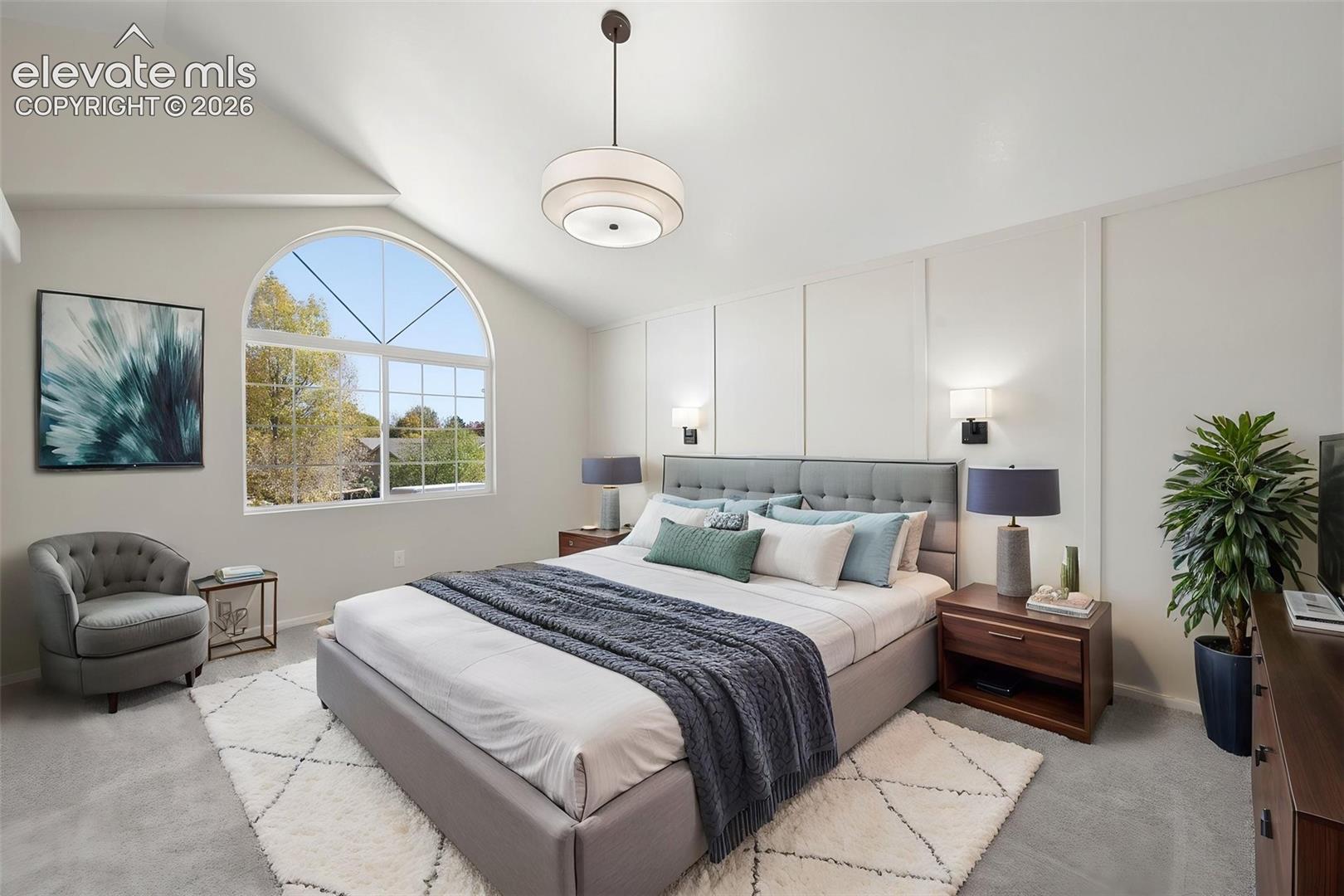Vaulted ceilings, arched window, wall-paneling detail, drum pendant lighting, and wall-mounted sconces
