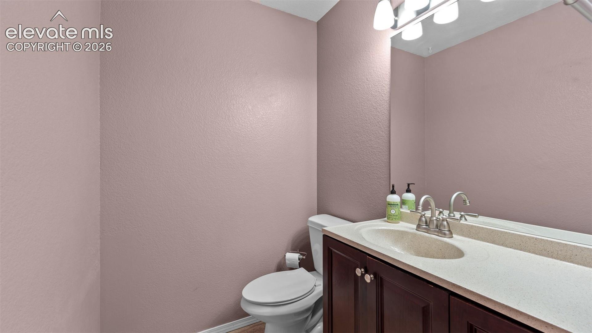 Dark wood-finish vanity with an integrated basin, light-toned solid surface countertop, polished chrome faucet, and expansive wall-mounted mirror