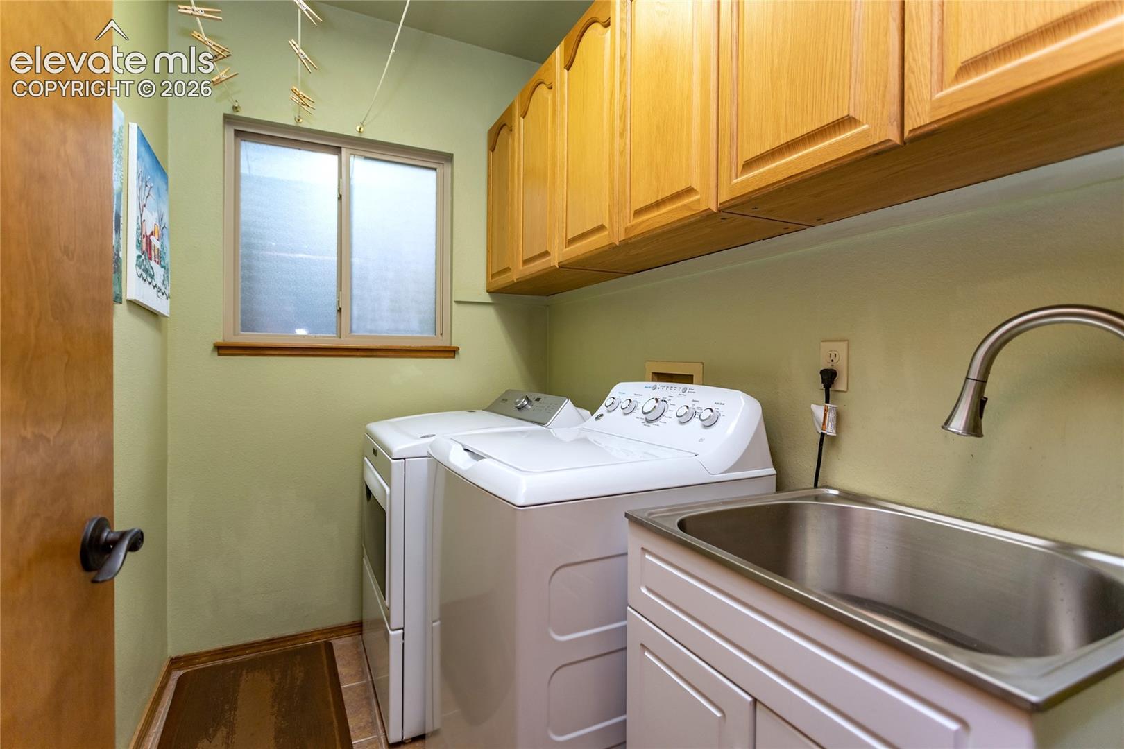 Main Level Laundry Room features Clothes Washer and electric Dryer, handy Sink, Window and plenty of Cabinet Space 