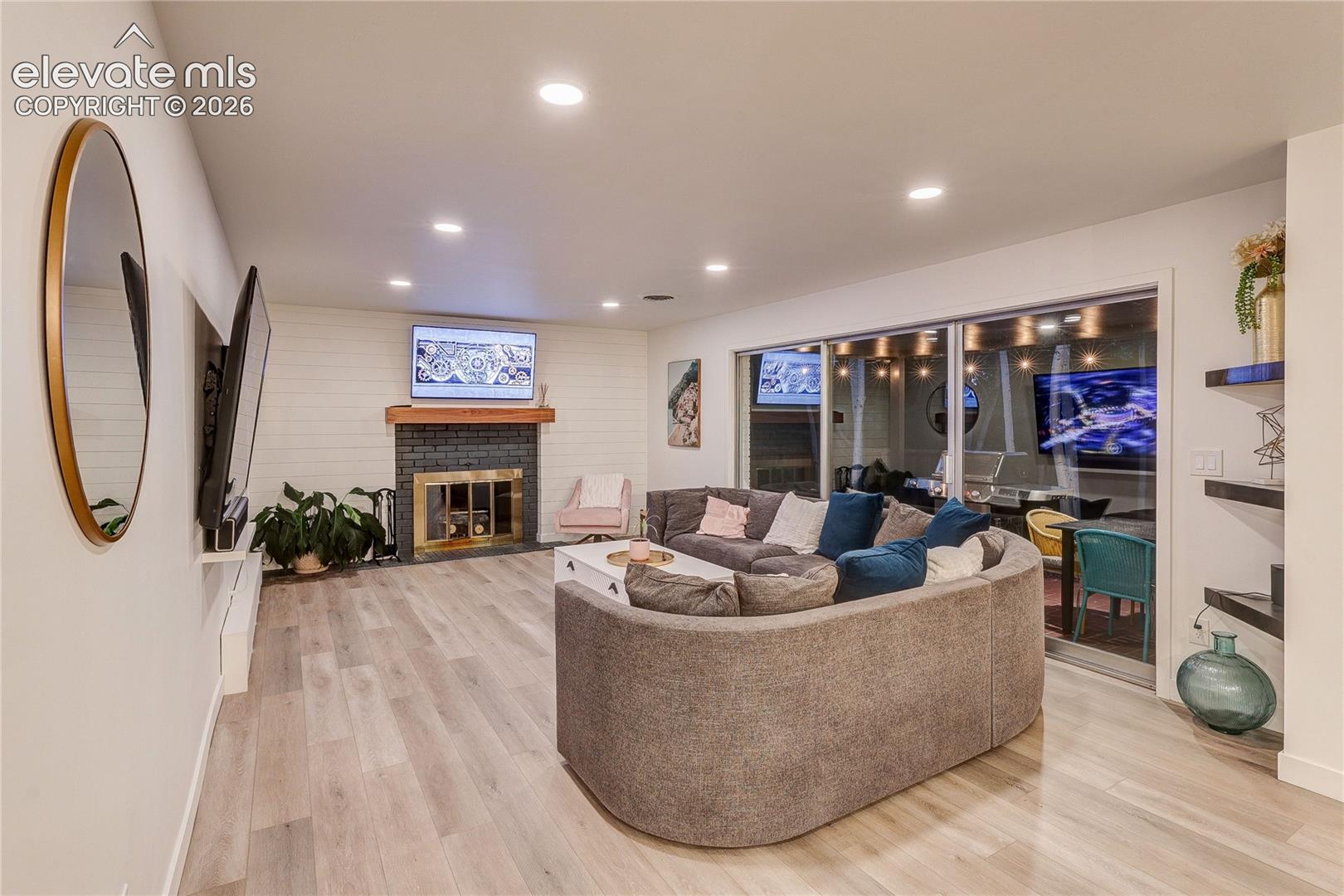 Recessed lighting illuminates the wood-finish flooring and shiplap accent wall