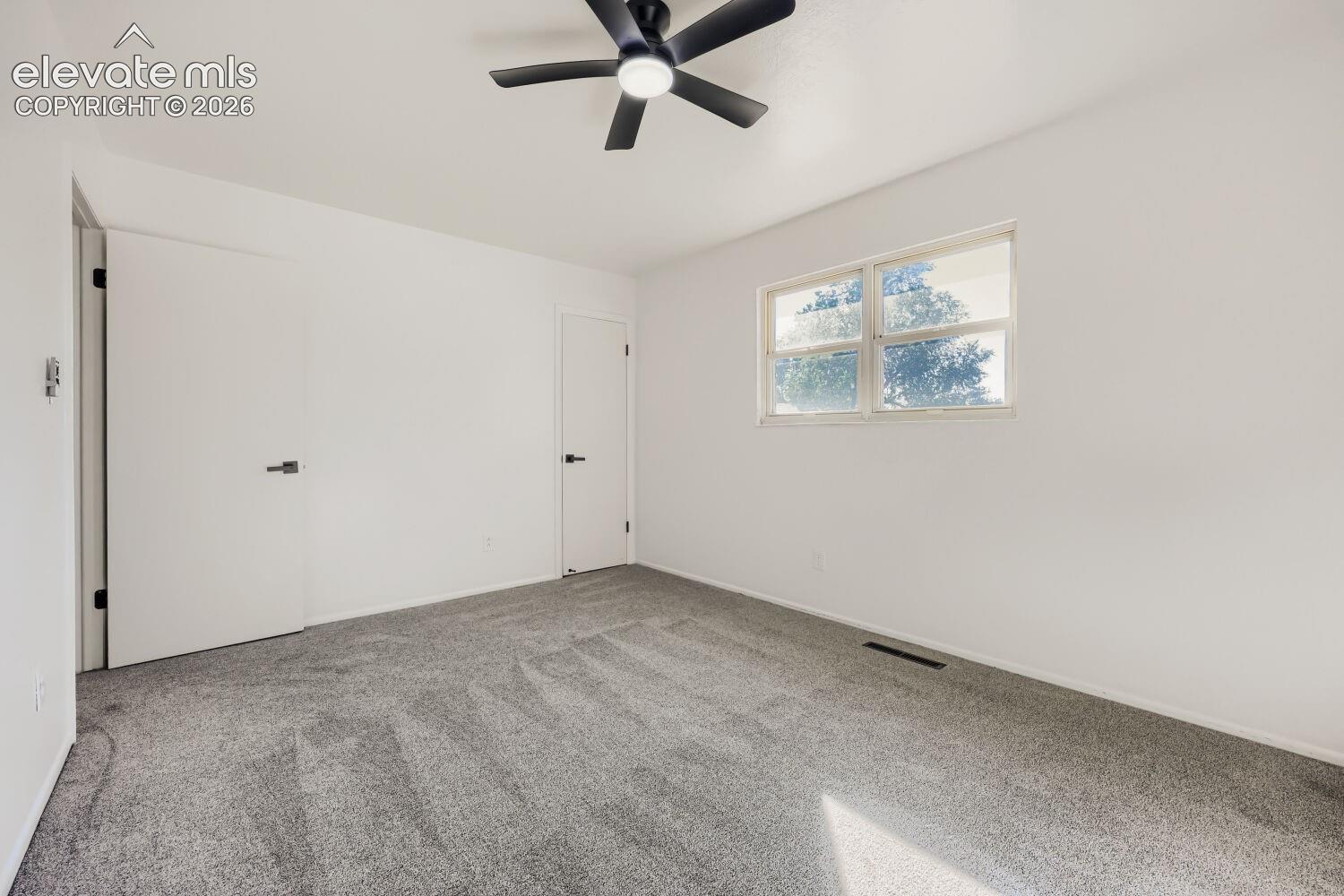 Wall-to-wall carpeting, ceiling fan with light fixture, window with natural light, and contemporary doors with black hardware