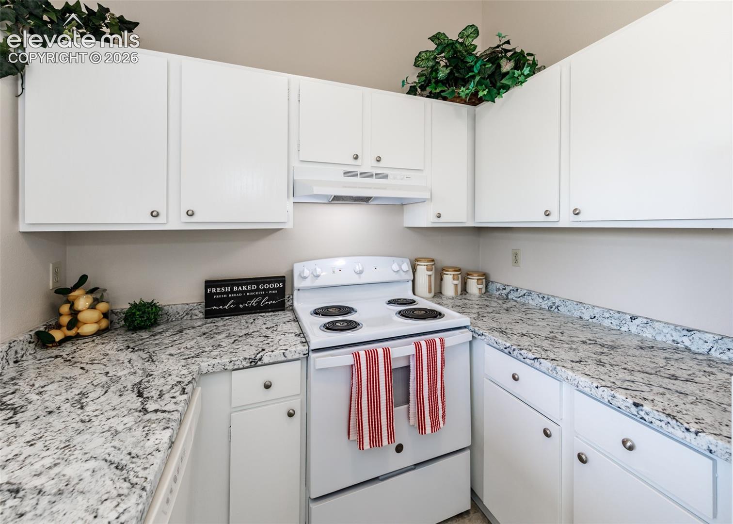 White cabinetry with silver hardware, speckled stone-finish countertops, white electric range, and a white range hood