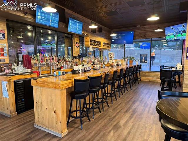 Community bar area with an ornate ceiling, wine cooler, butcher block counters, wooden walls, and hanging light fixtures