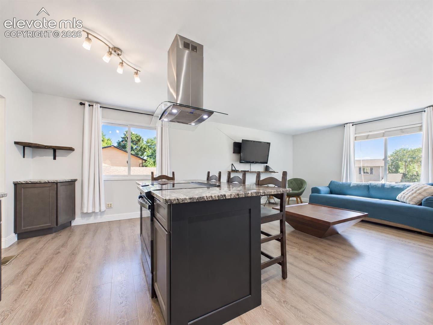 Another expansive view showcases the island-centered kitchen opening directly to the living area, creating a flexible gathering space with windows on multiple sides.