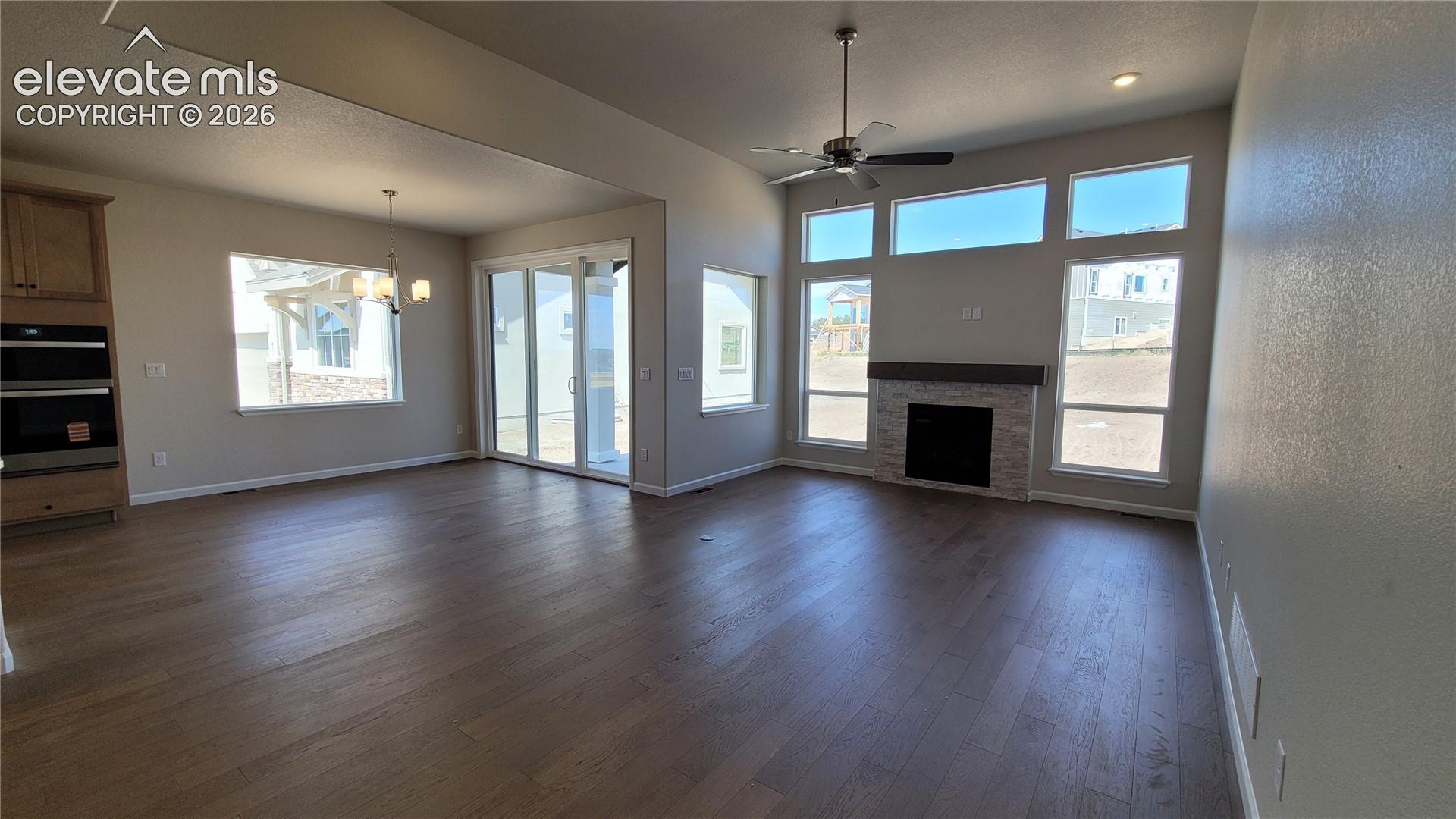 Great Room with engineered wood flooring, floor outlet, LED lighting, ceiling fan, cozy gas fireplace with a wood mantel, and stacked stone surround!
