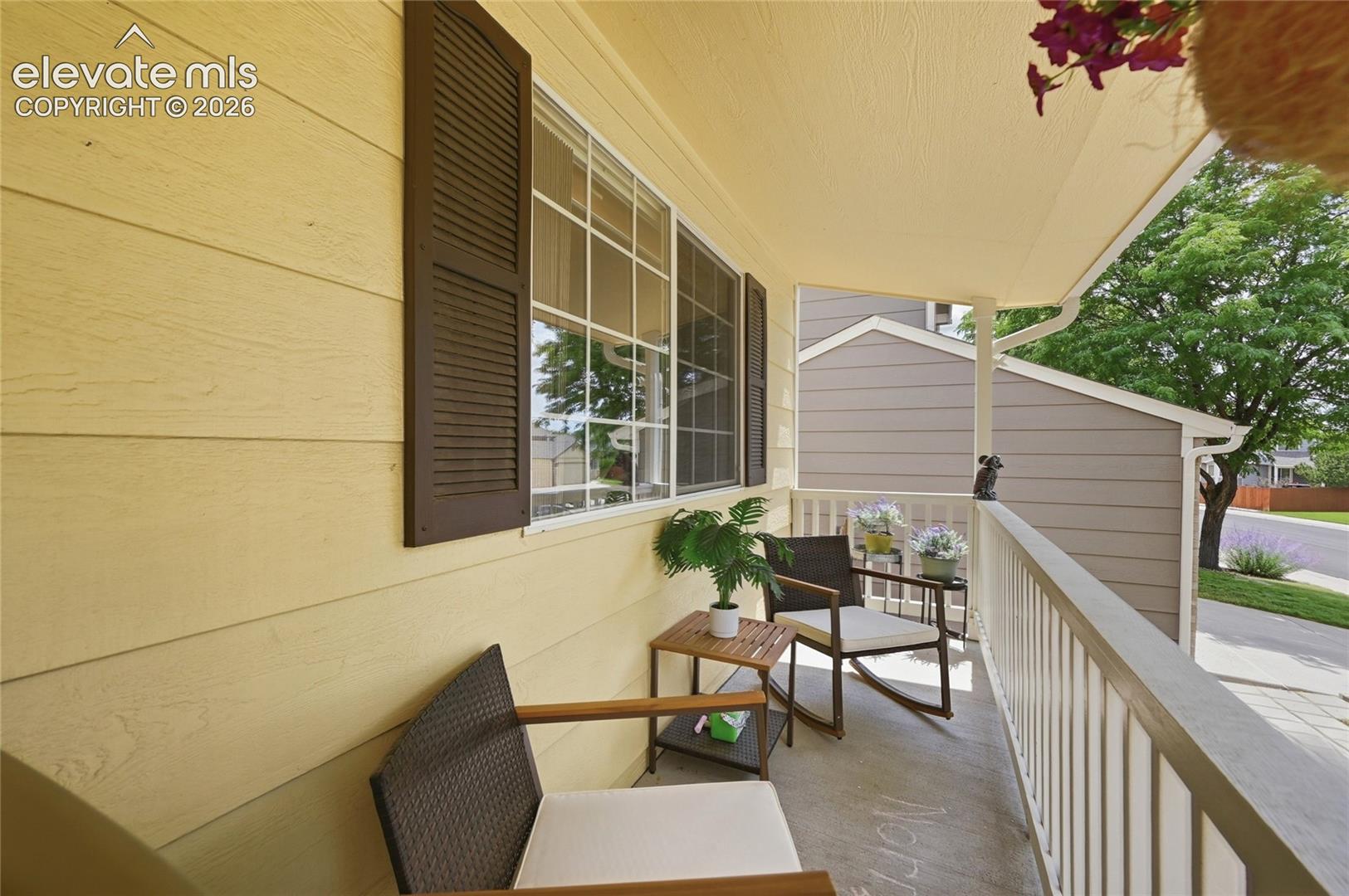 Covered balcony featuring horizontal lap siding, paneled shutters, grid-pattern windows, and a painted metal railing
