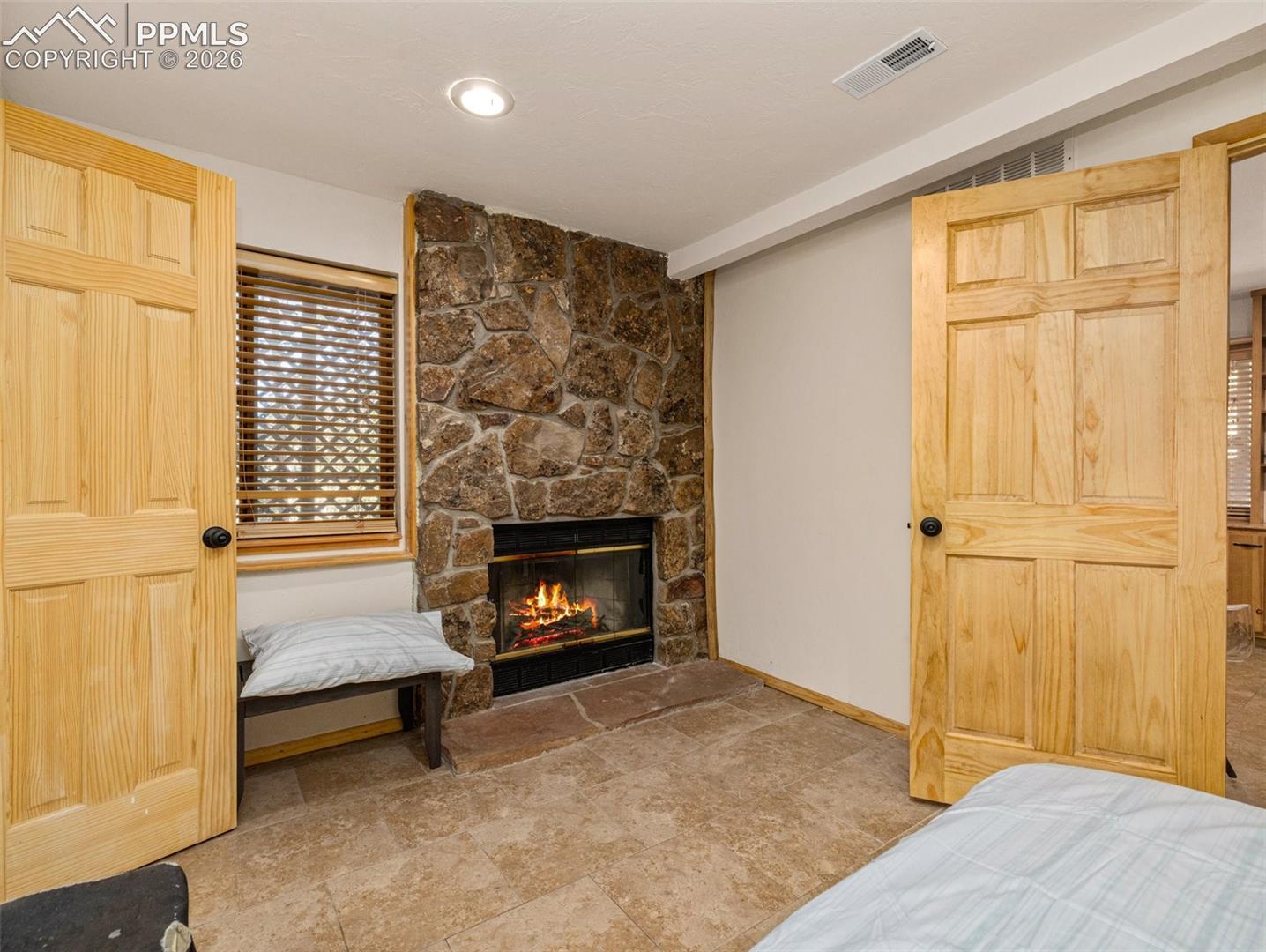 Bedroom with a stone fireplace and vaulted ceiling