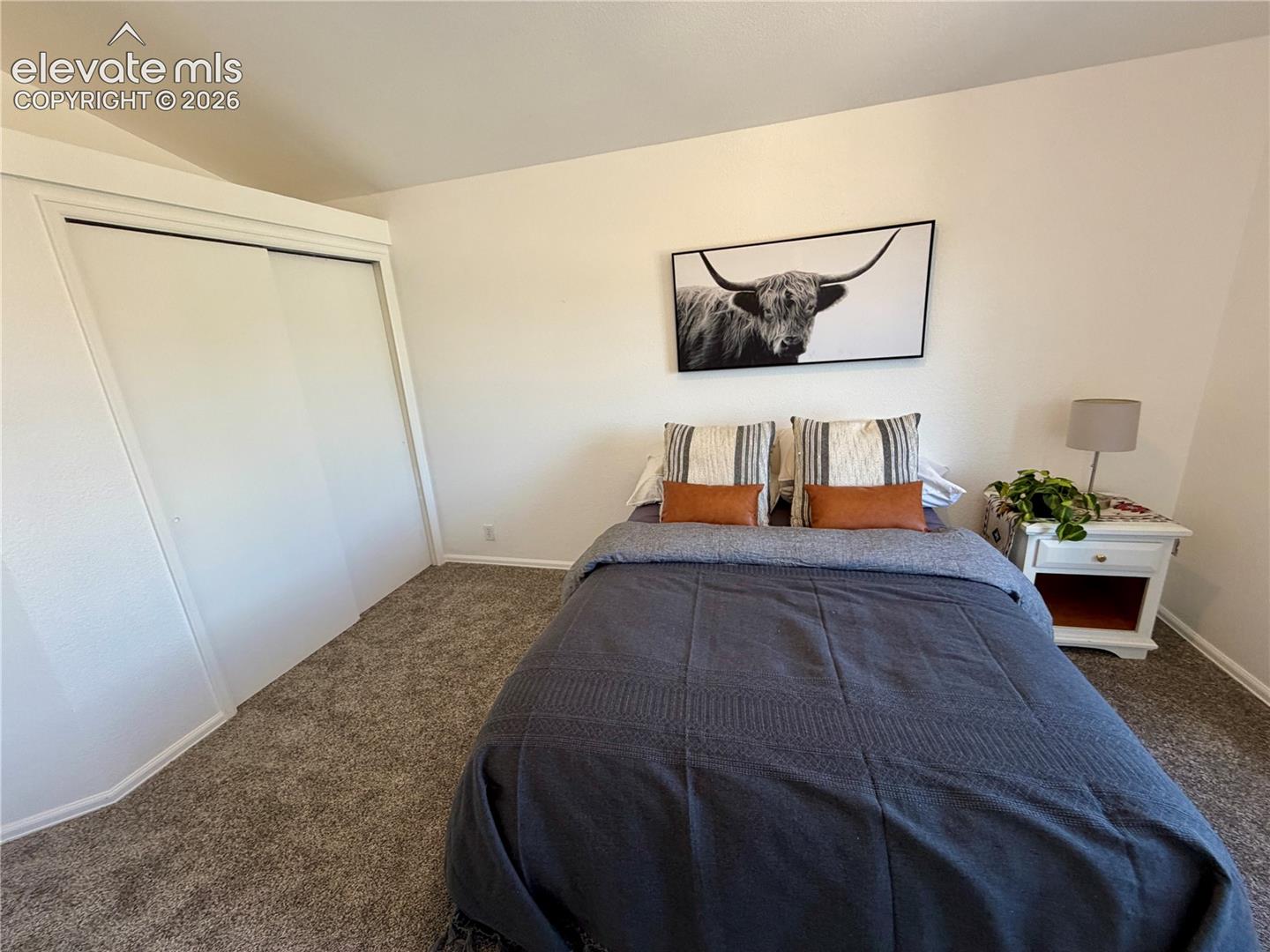 Upstairs Bedroom featuring neutral wall tones, textured carpet flooring, and a built-in closet with sliding panel doors