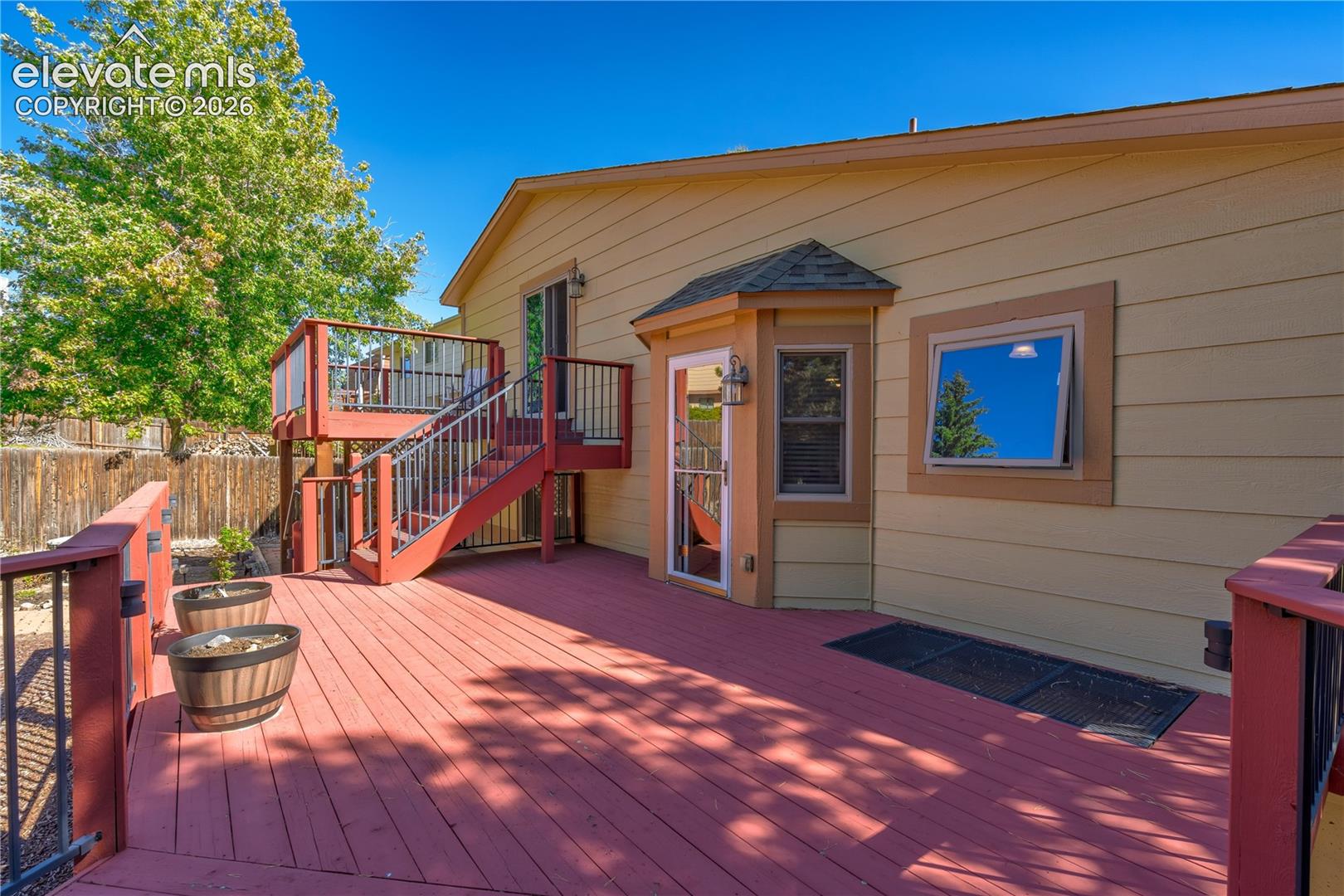 Multi-level wood deck with black metal railings and a bay window feature