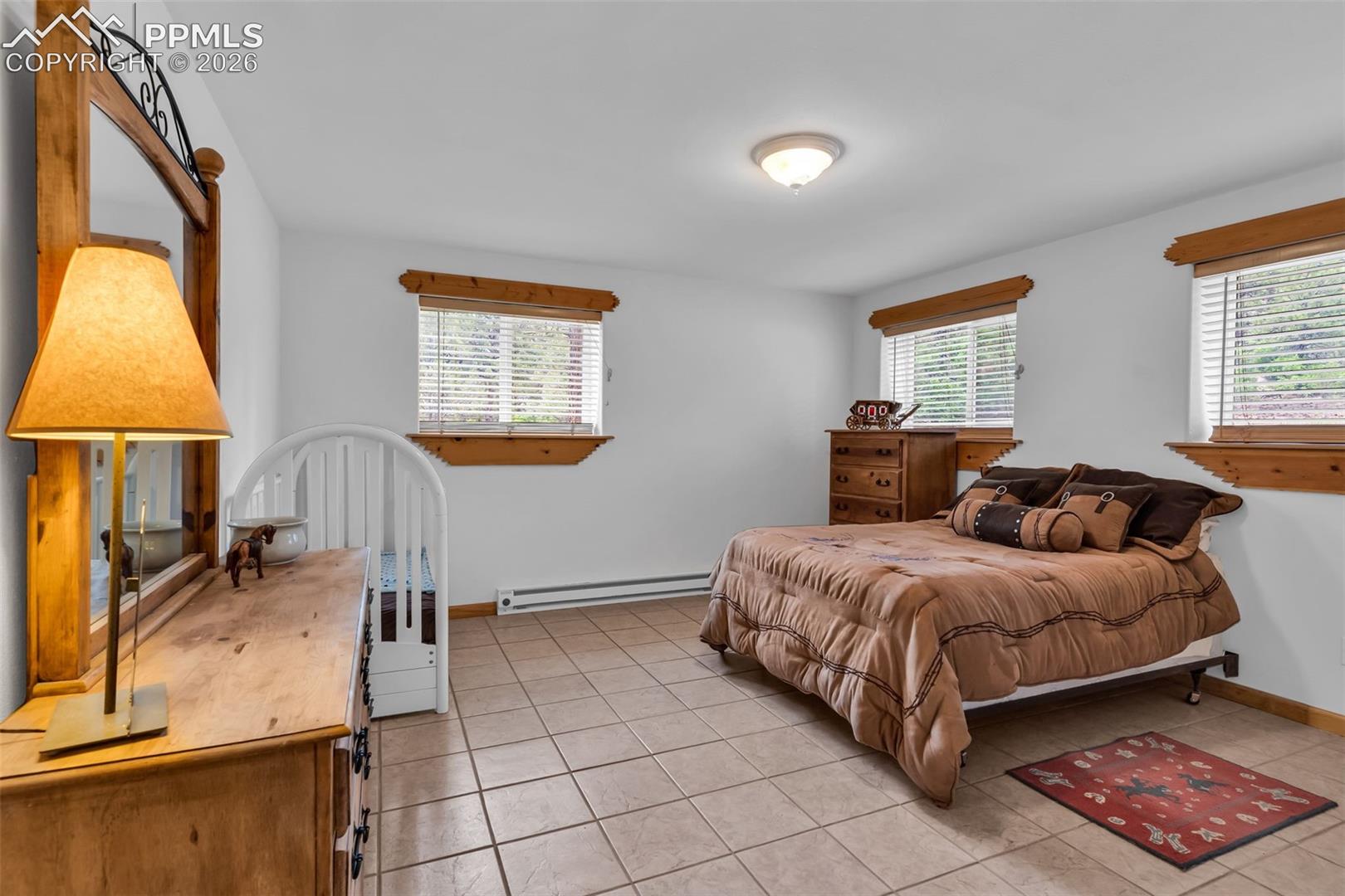 Large lower level bedroom with tile floors and garden level windows