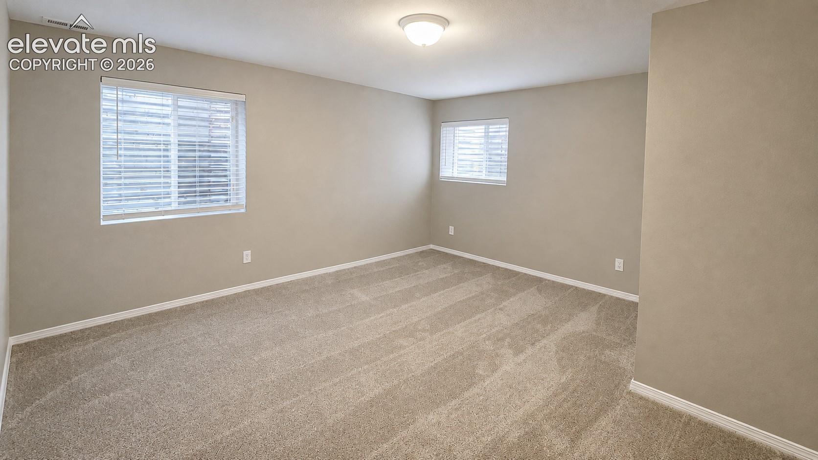Neutral paint palette, textured carpeting, multiple windows with blinds, and flush-mount ceiling lighting