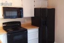 Kitchen featuring white cabinetry, and black appliances including a refrigerator, over-the-range microwave, and electric range