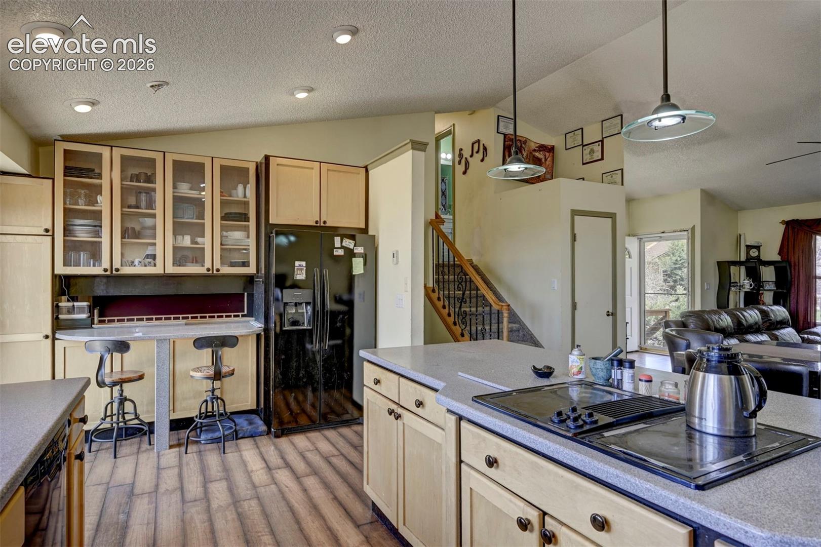 Kitchen featuring wood-finish flooring, recessed lighting, light-toned cabinetry, and a built-in cooktop on a solid surface countertop