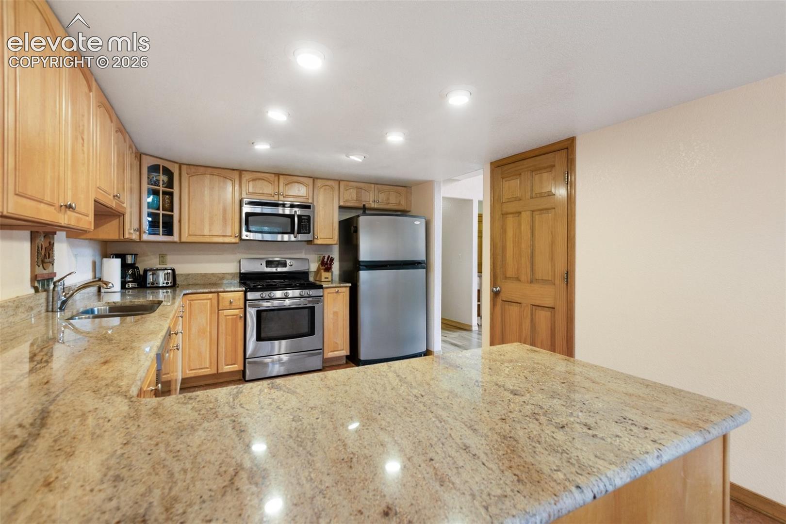 Kitchen featuring wood cabinetry, light-toned countertops, stainless steel appliances, and recessed lighting