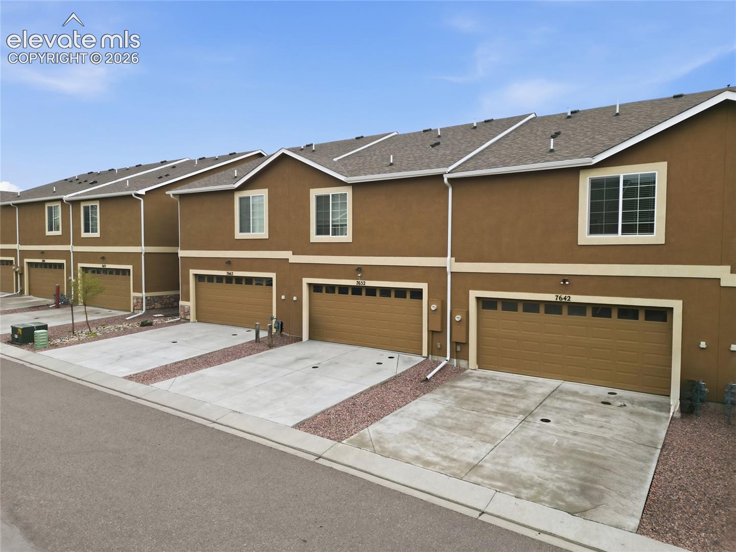 Multi-unit exterior featuring stucco siding, multi-gabled rooflines, attached multi-car garages, and concrete driveways
