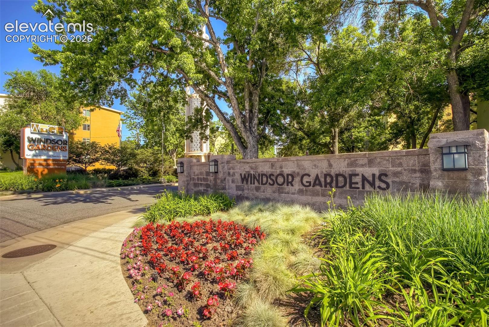 Stone wall entry with integrated sconce lighting, featuring "Windsor Gardens" lettering