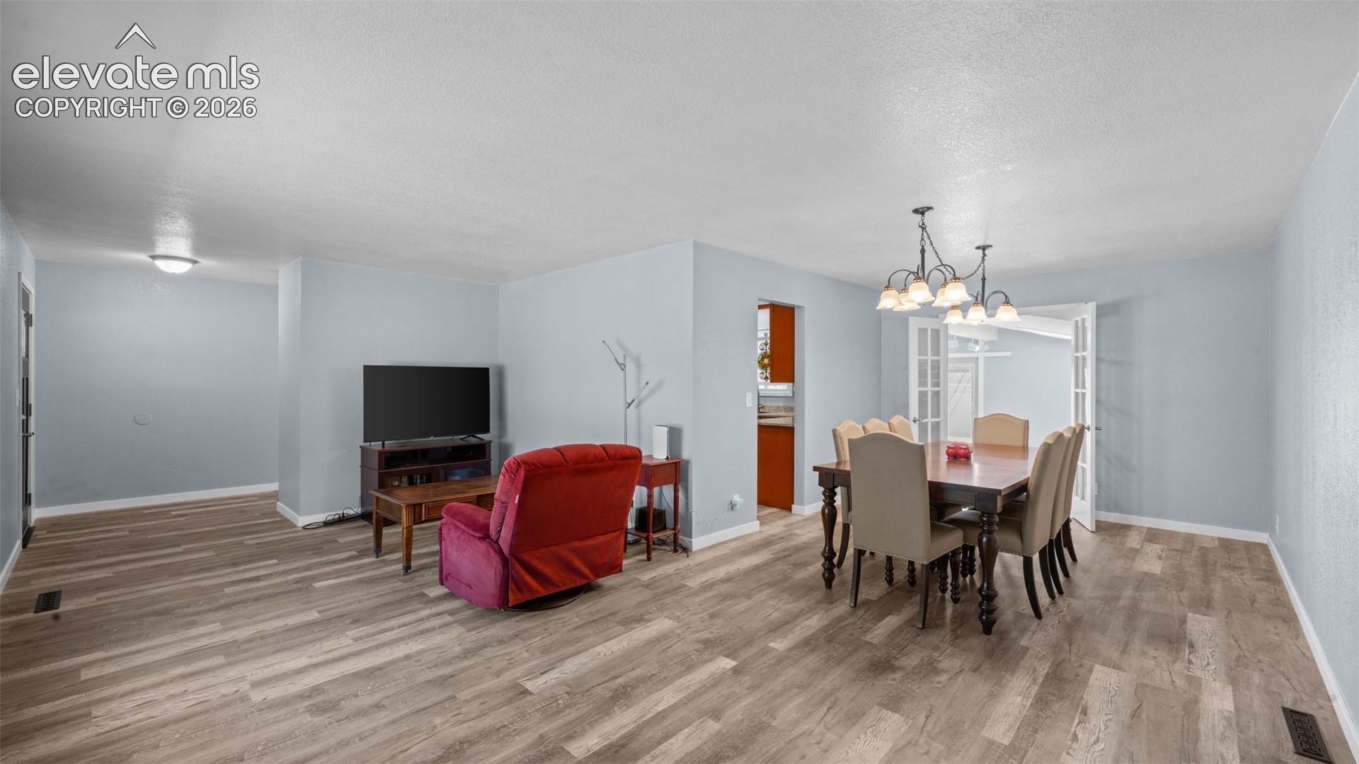 Open-concept living and dining area featuring wood-finish flooring throughout, light blue wall paint, and white baseboards