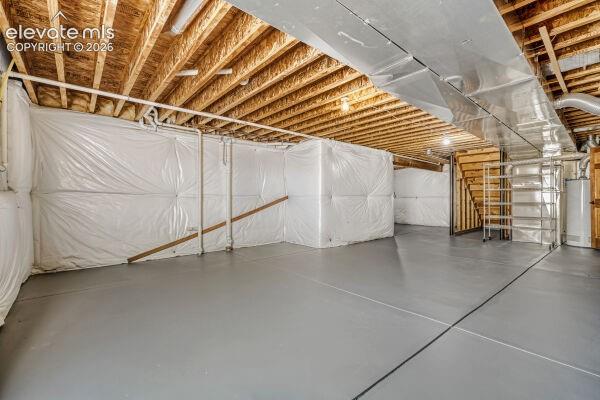 Unfinished basement featuring a painted concrete floor, exposed wood ceiling joists, and insulated perimeter walls