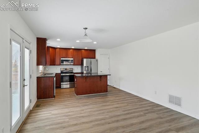 Kitchen with stainless steel appliances, plenty of natural light, recessed lighting, a kitchen island, and dark countertops