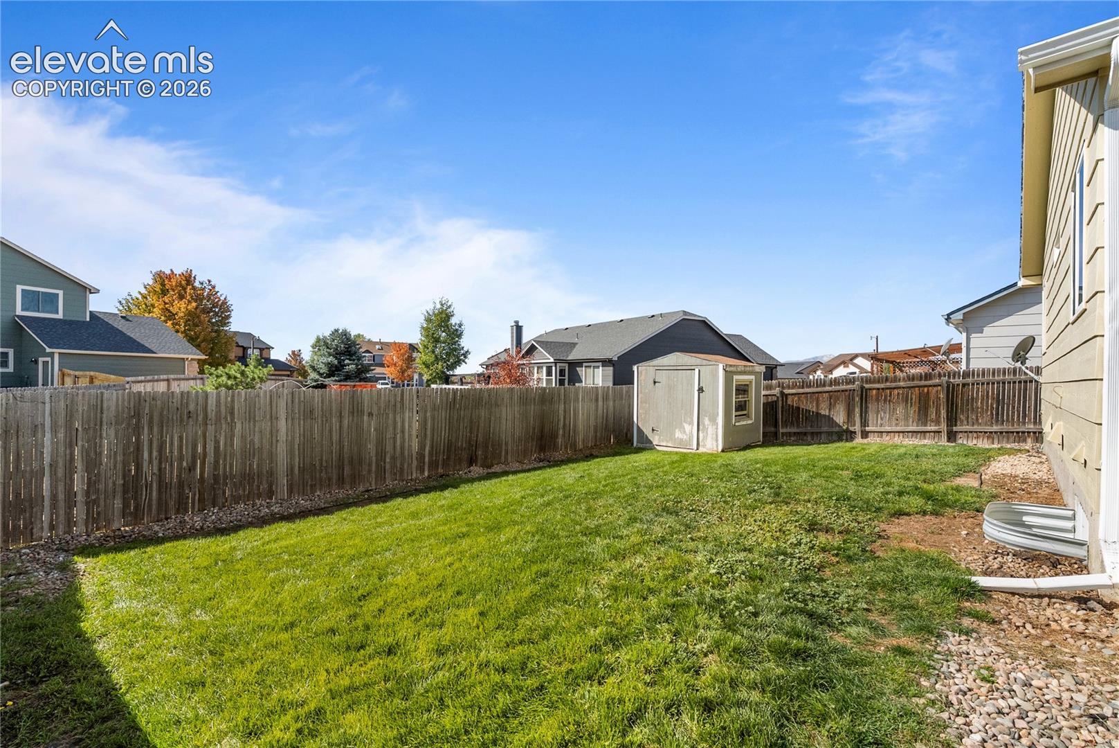 Expansive fenced backyard with a storage shed and gravel border