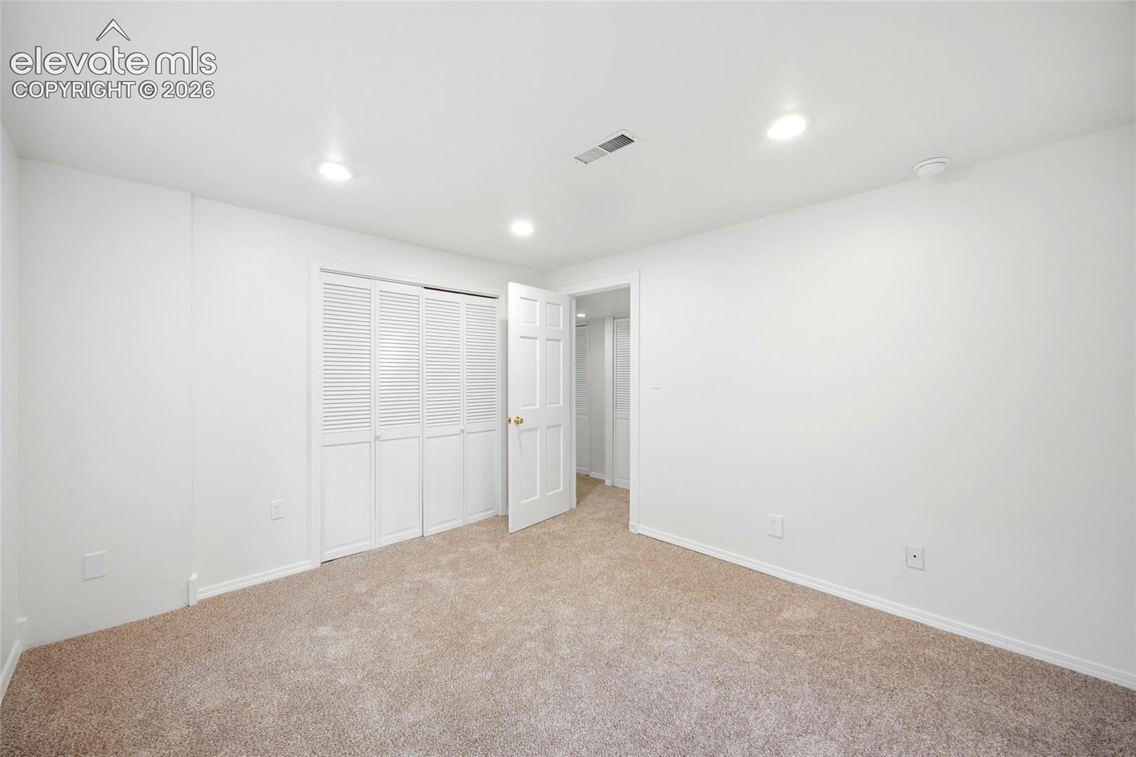 Interior space featuring wall-to-wall carpeting, recessed ceiling lighting, and a closet with white louvered bifold doors