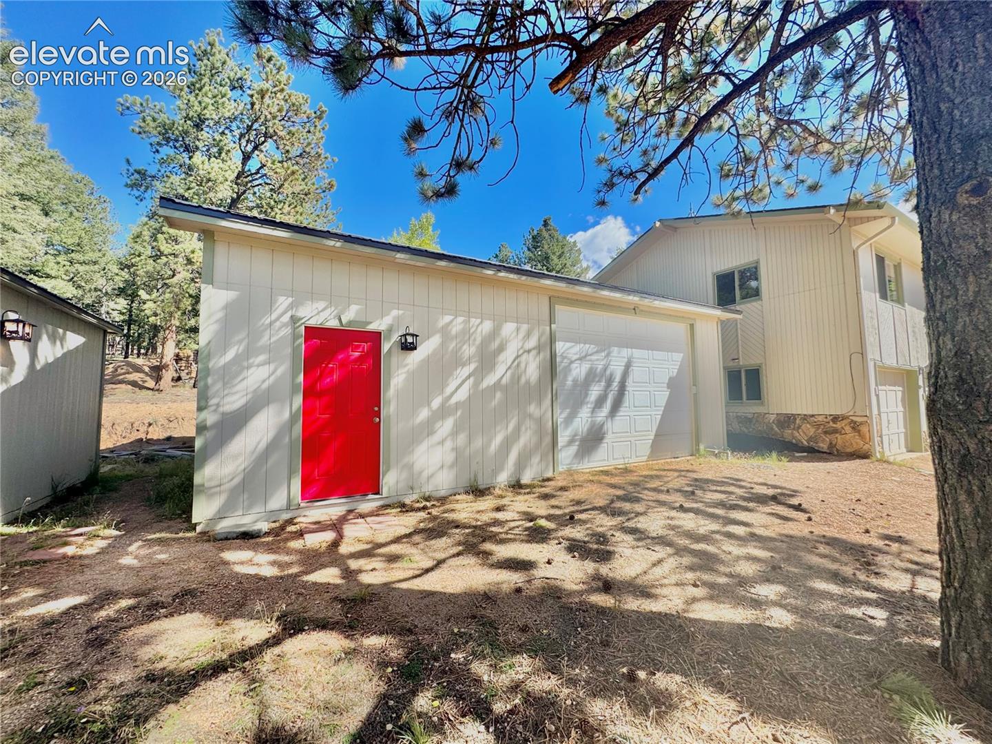 Detached Garage/Shop with red entry door, exterior lighting, and a single-car garage