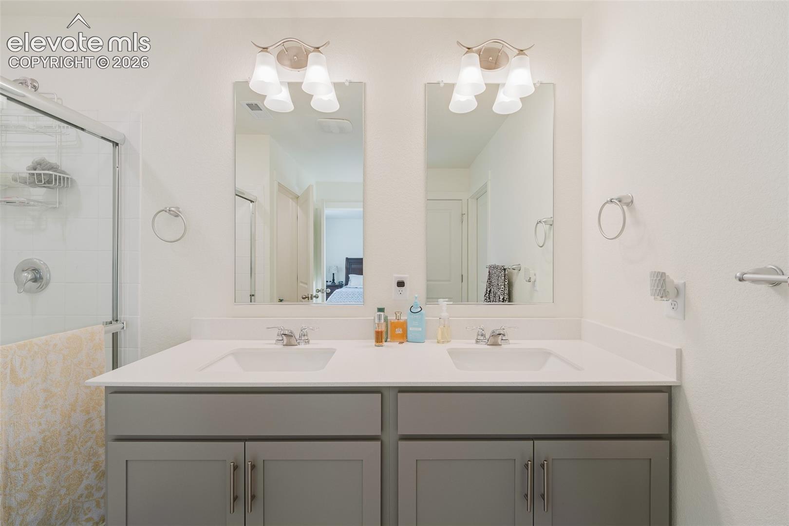 Upper Level Primary Bathroom with a dual sink vanity, mirrors, and an enclosed tiled shower.