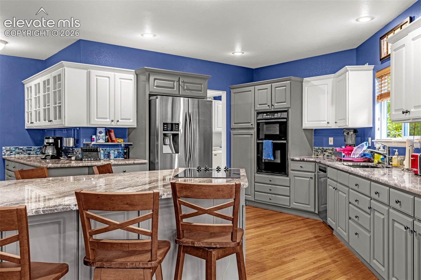 Granite-finish countertops, stainless steel appliances, built-in double oven, wood-finish flooring, and ample cabinetry