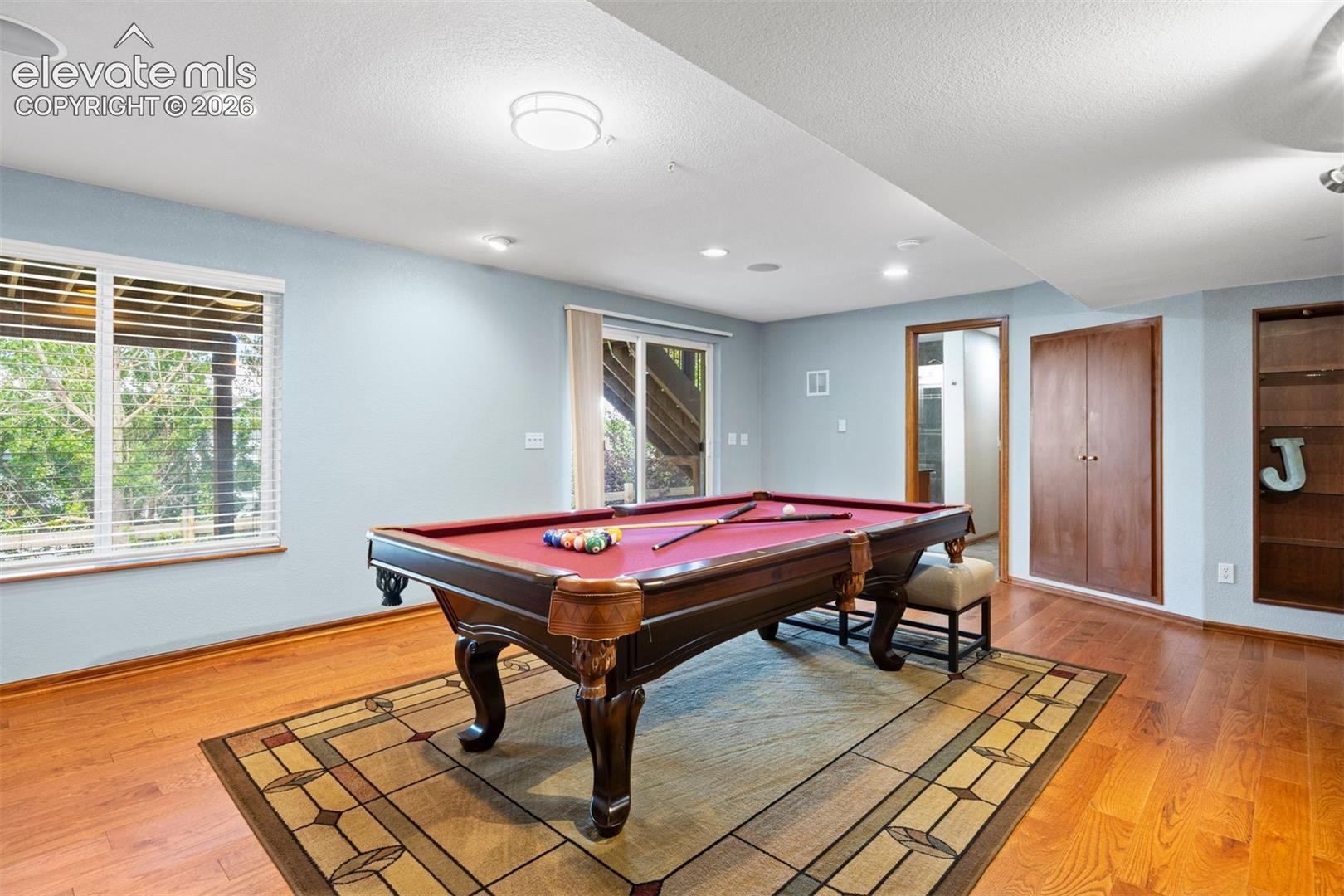 Entertainment room featuring wood-finish flooring, recessed lighting, and a window with natural light