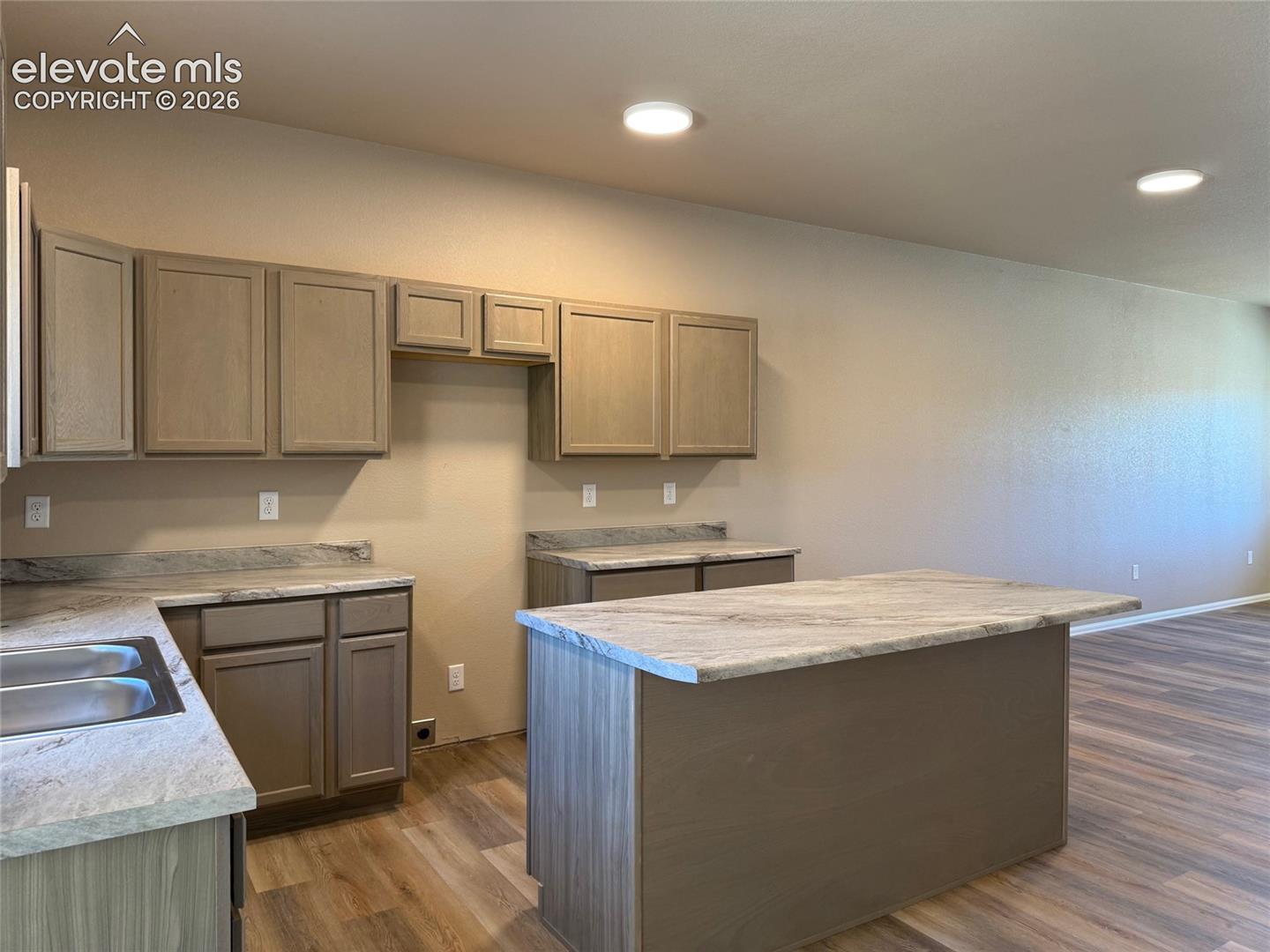 Kitchen featuring wood-finish cabinetry, light-toned countertops, and wood-finish flooring
