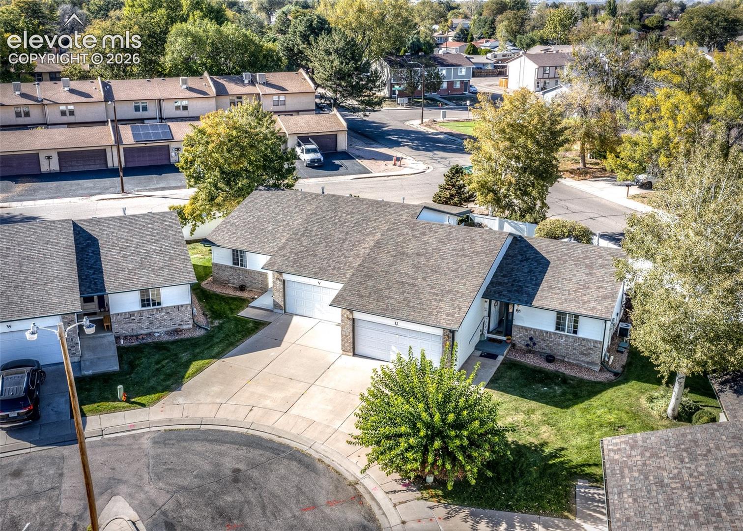 Single-story structure featuring a multi-pitched shingled roof, stone masonry accents, an attached two-car garage, and concrete driveway