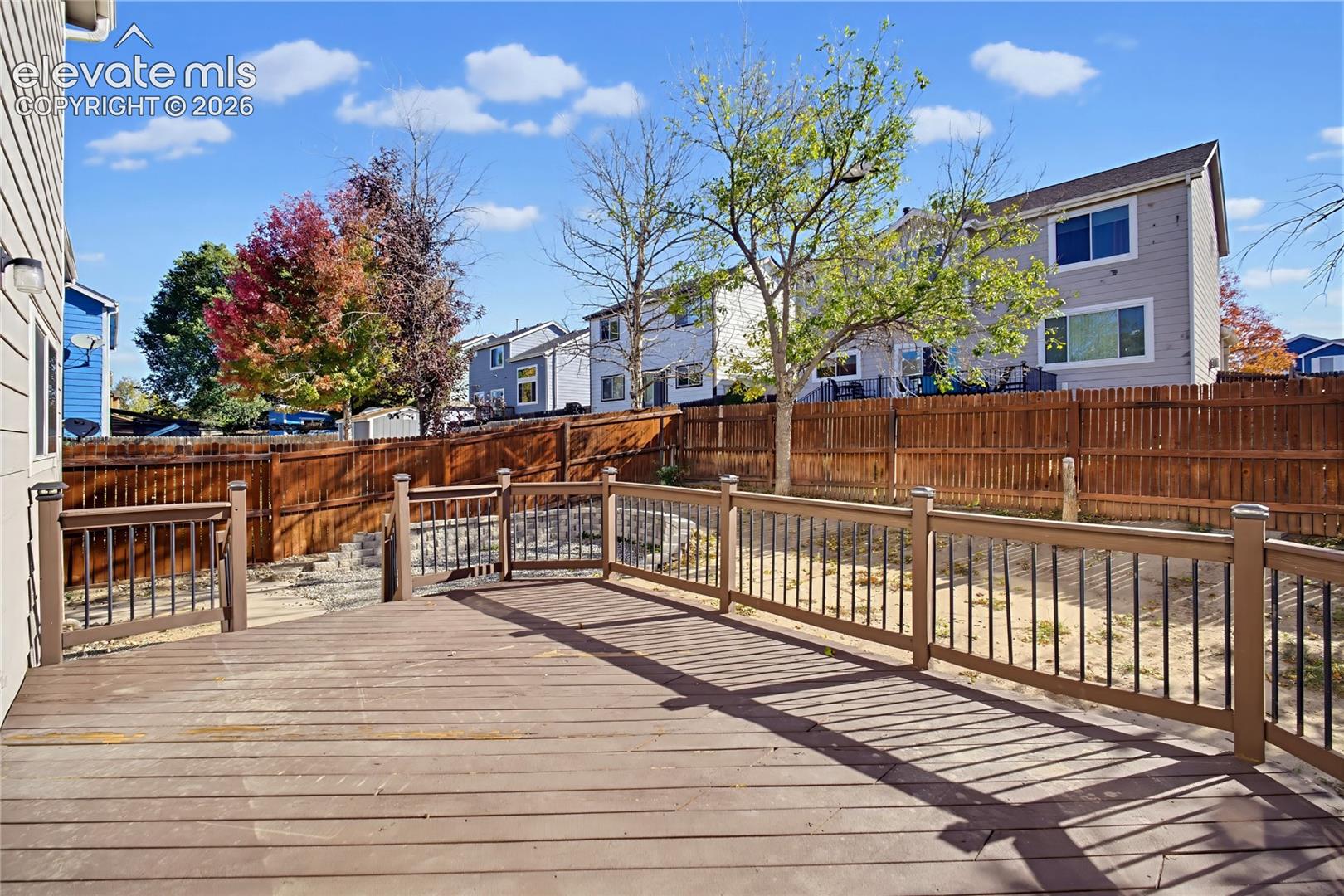 Spacious wood-tone deck featuring black metal balusters and a perimeter privacy fence