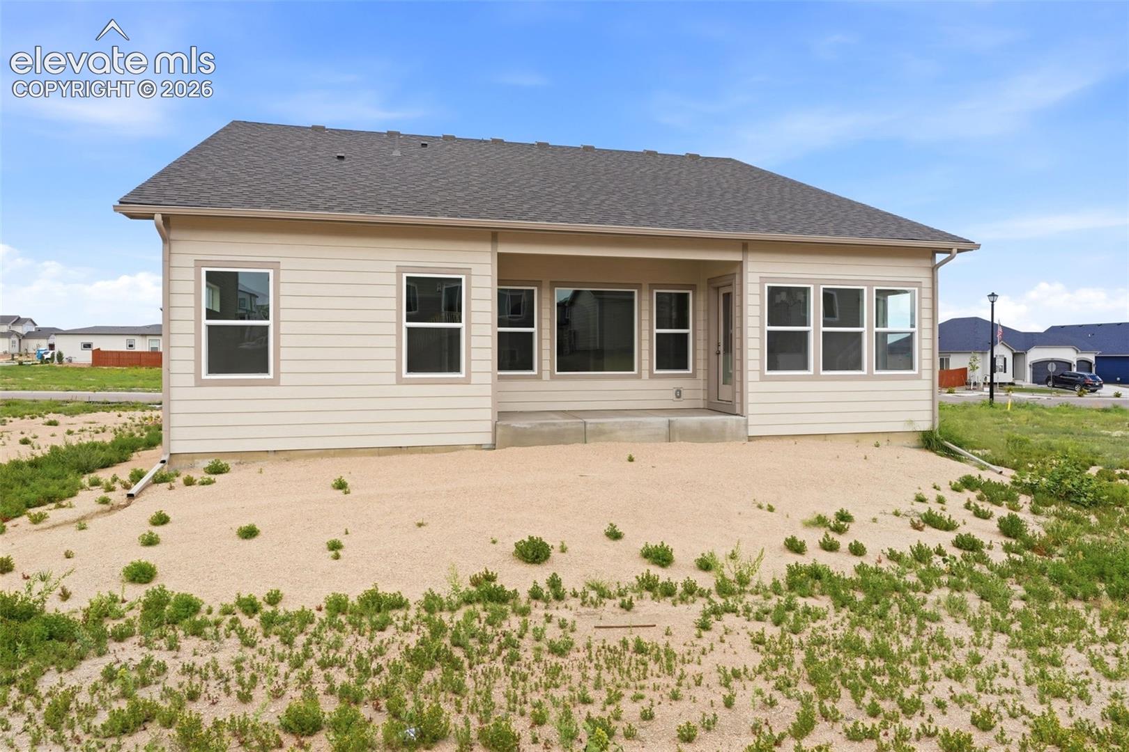 Single-story exterior featuring horizontal siding, a composite shingle roof, a covered rear patio, and multiple energy-efficient style windows