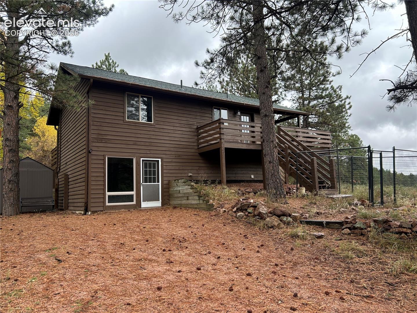 Rear driveway/parking area, with dog run and stairs to deck/main level to the right.