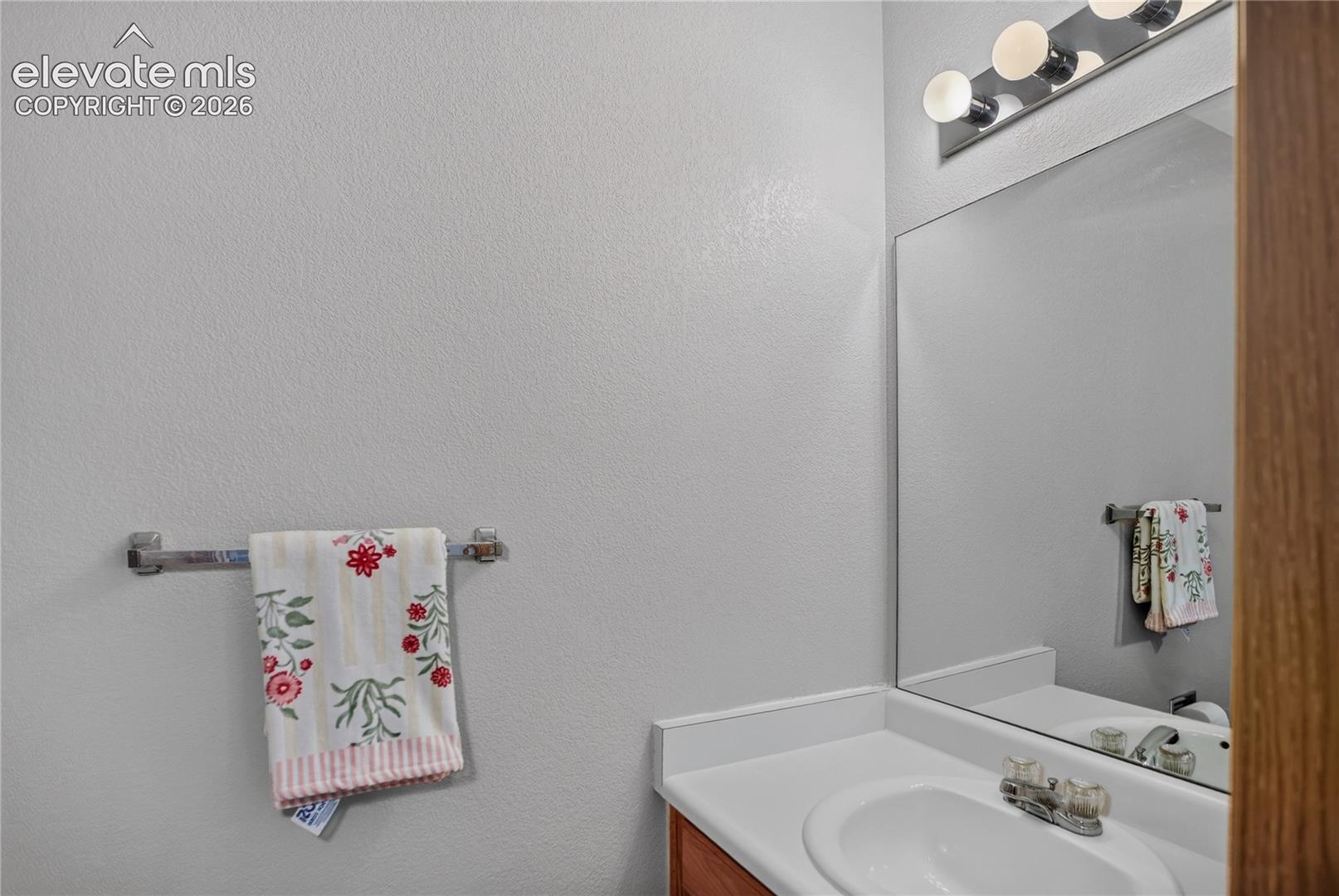Vanity with an integrated sink, polished chrome faucet, and a wall-mounted mirror