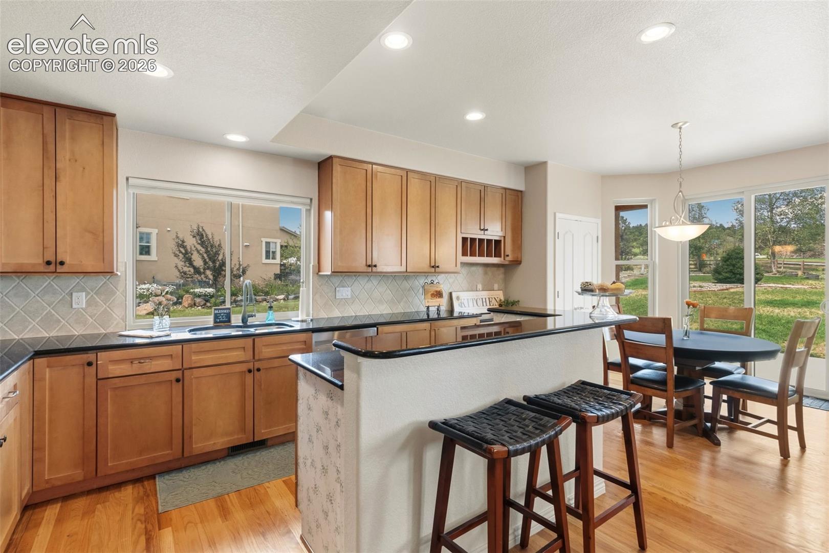 Open-concept kitchen featuring wood-finish flooring, granite counter, desk area recessed lighting, and ample natural light