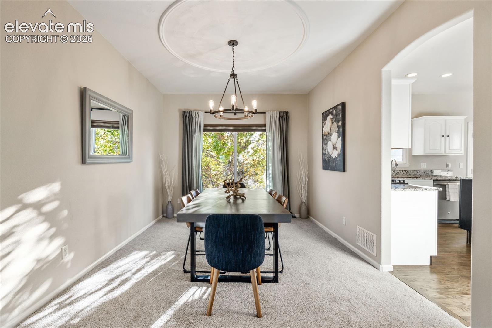Dining area featuring a decorative ceiling medallion, an industrial-style metal chandelier, and sliding glass doors