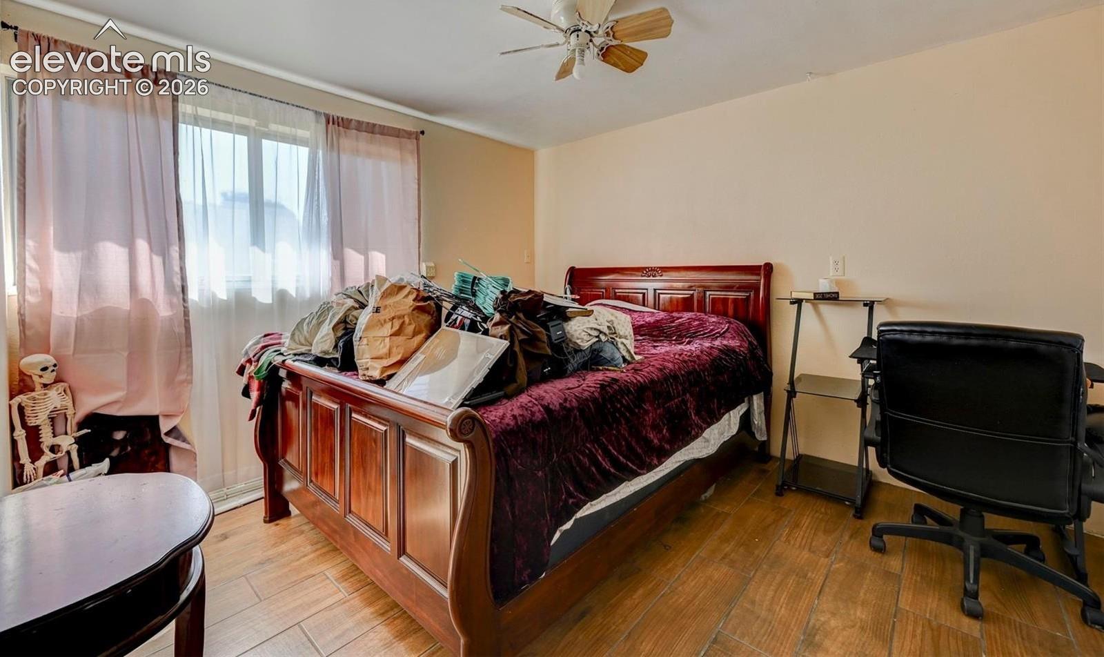 Wood-finish tile flooring, ceiling fan with integrated light fixture, and large sliding window with neutral wall finishes