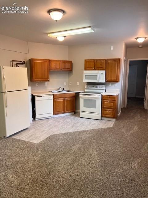 Kitchen featuring wood cabinetry, white appliance suite, dual-basin sink, and wood-finish flooring
