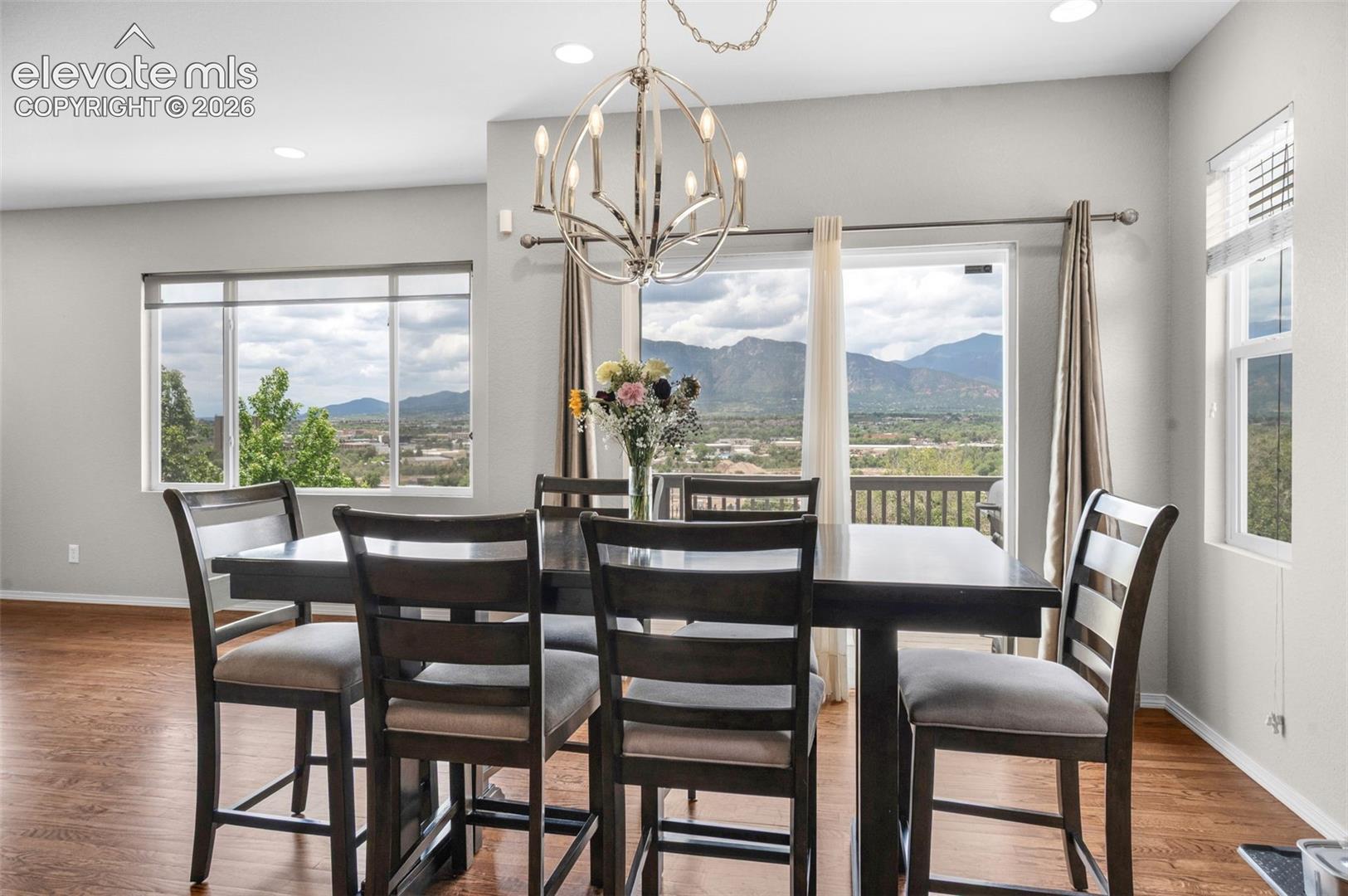 Dining area with wood-finish flooring, recessed lighting, and a contemporary chandelier. Walk Out to a 10'x10' deck.