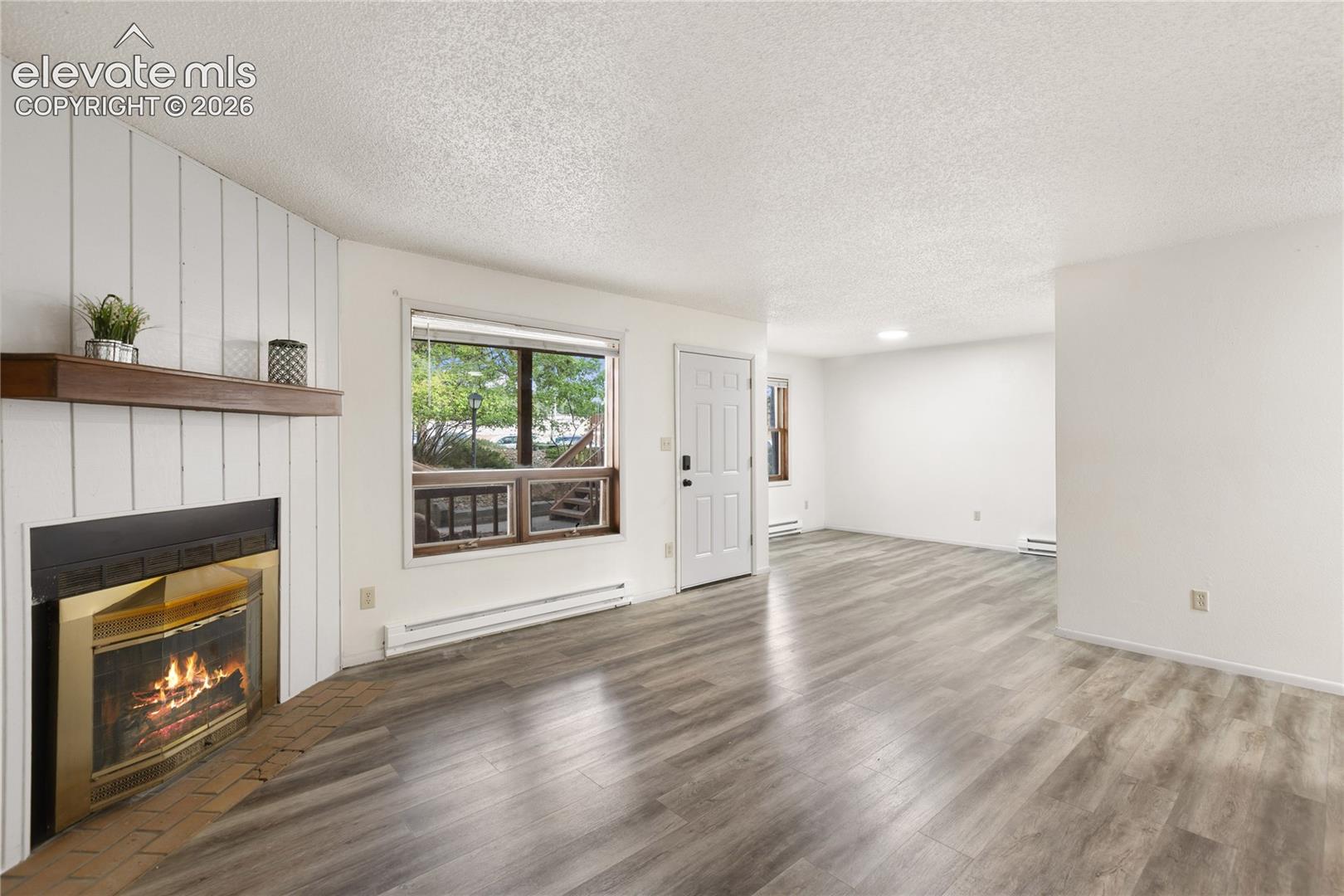 Open living space featuring wood-finish flooring and a fireplace with a wood mantel