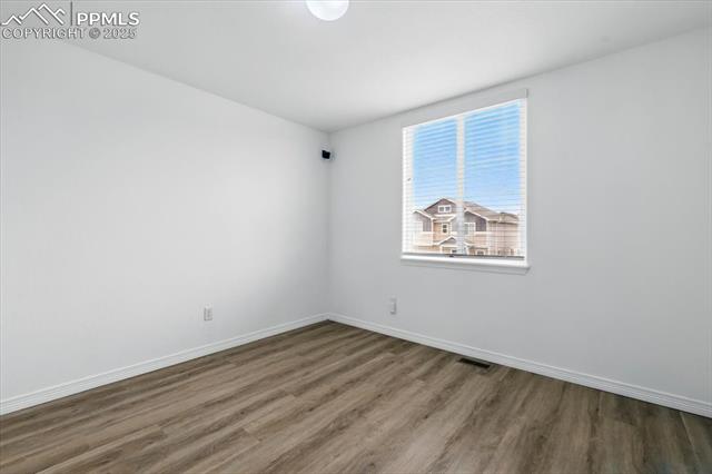 Unfurnished room with wood finished floors and baseboards