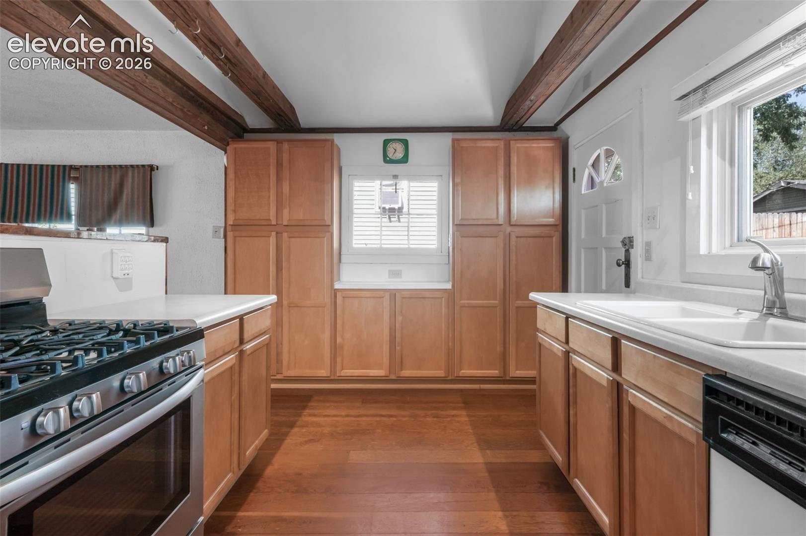 Kitchen with wood-finish flooring, wood cabinetry, white countertops, and a stainless steel oven range