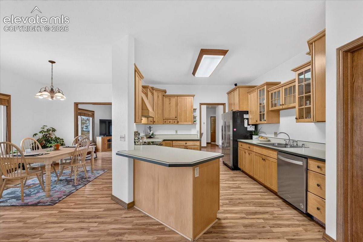 Kitchen featuring natural wood cabinetry, a breakfast bar, solid surface countertops, stainless steel appliances, and wood-finish flooring