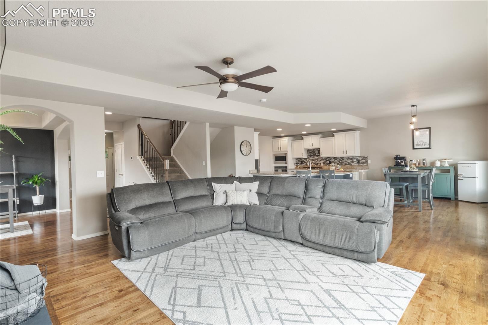 Living room with ceiling fan, recessed lighting, arched walkways, and light wood-type flooring