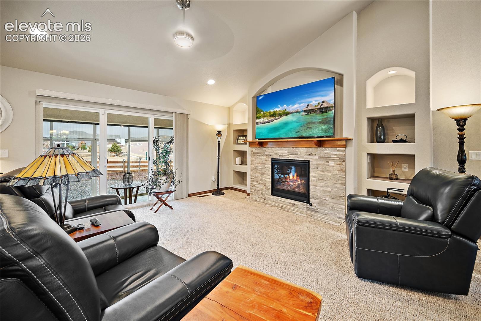 Living room with gas fireplace, stone surround and custom built-ins. Walk out to enclosed patio. 