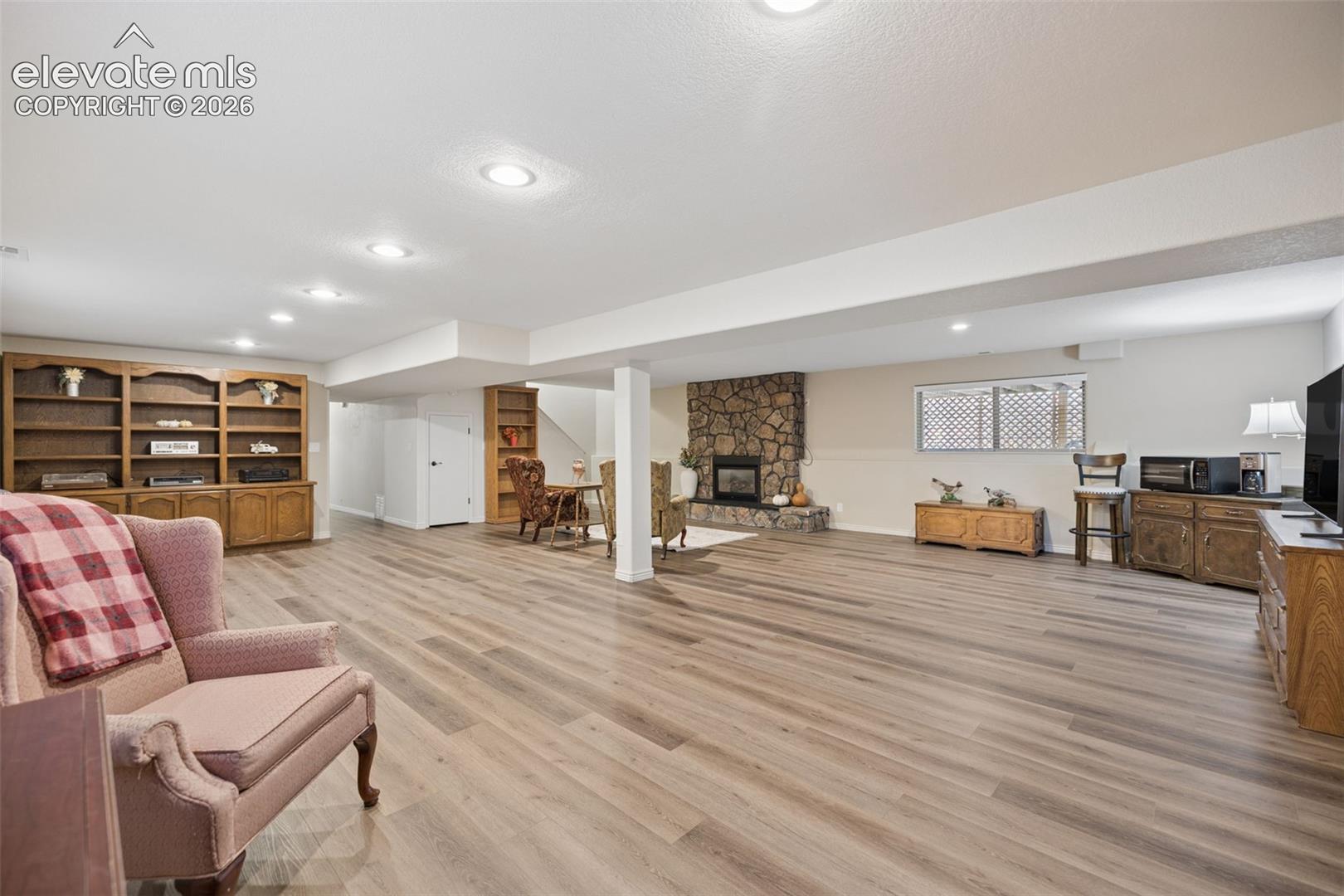 Spacious basement flex room with gas fireplace with stone surround and LVP flooring.
