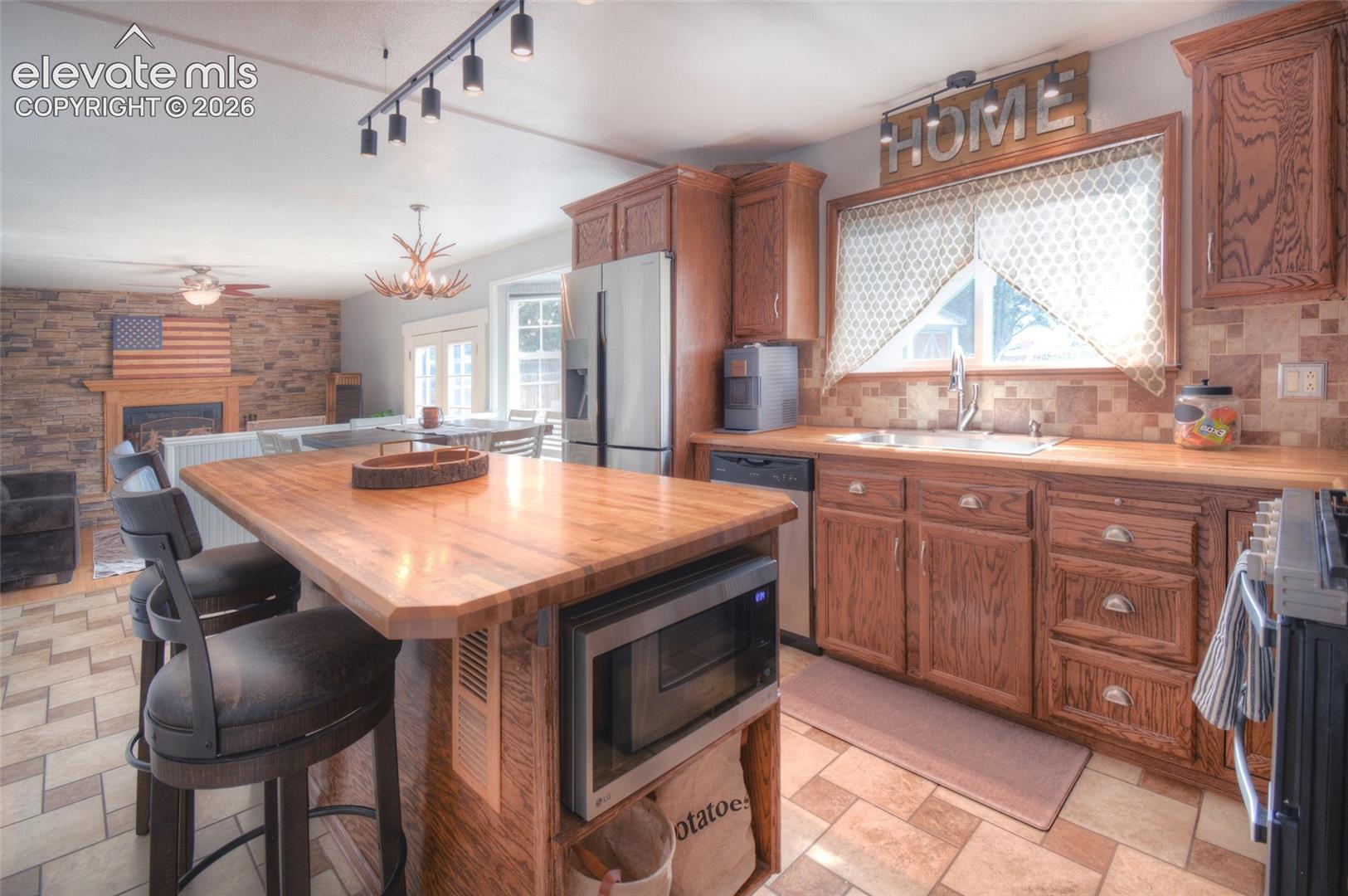 Large kitchen island with warm cabinetry, large window with view to the backyard and opens to the family room.
